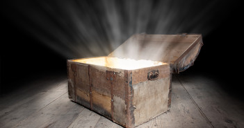 Ancient wooden treasure chest with the strong glow from inside.