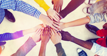 Circle of people putting hands of top of each others' hands