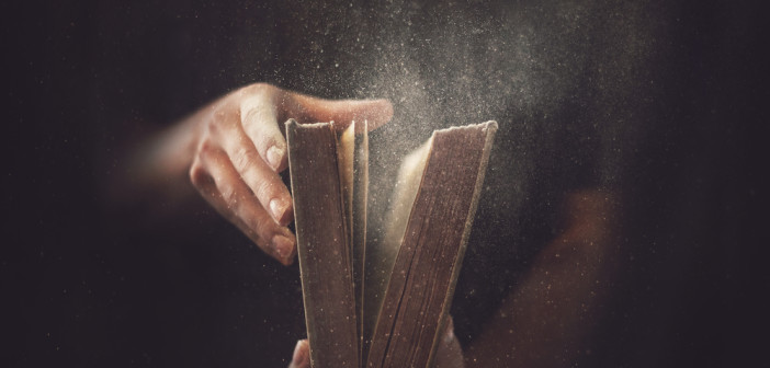 Holding an open book with dust coming out.