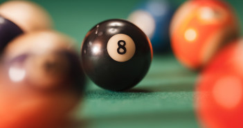 Pool ball with number 8 over green background.