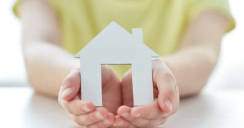 close up of happy girl holding paper house cutout in cupped hands