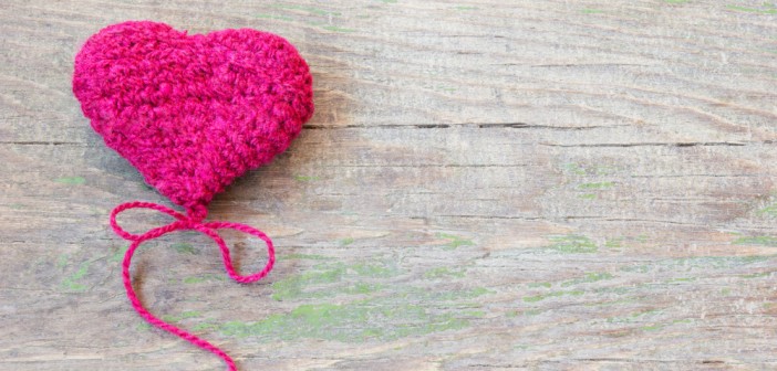 Knitted pink heart on a wooden background
