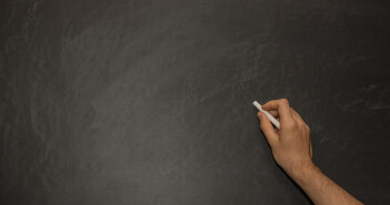 hand writing with white chalk on black chalkboard